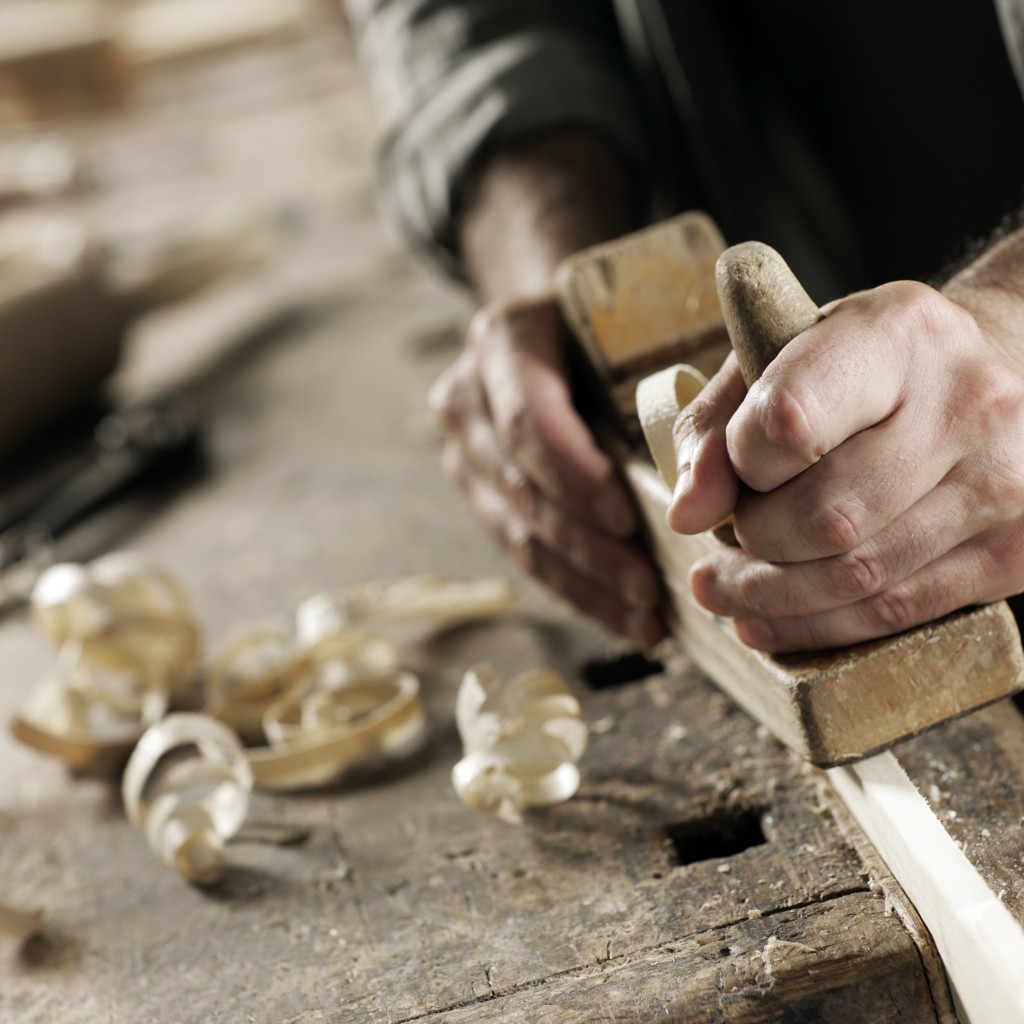 Hands of a carpenter planed wood, workplace